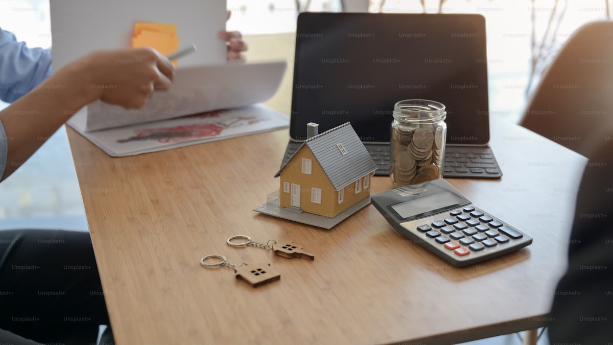 House model, calculator, keys and financial documents on desk for mortgage calculation