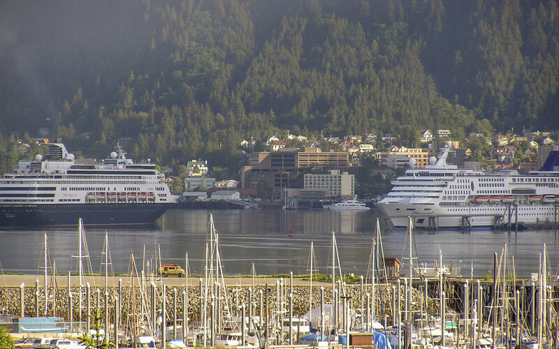 Downtown Juneau Alaska waterfront with cruise ships docked in the harbor and forested mountains behind the city