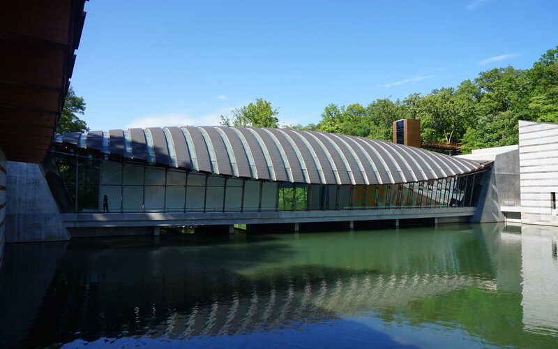 Exterior of the Crystal Bridges Museum of American Art in Bentonville Arkansas with its distinctive curved roof over a reflecting pond