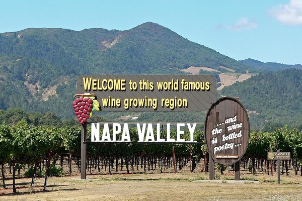 Welcome to Napa Valley sign with vineyards and mountains in California wine country