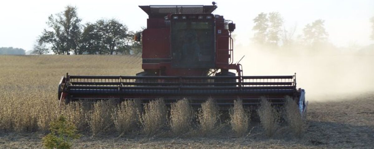 Combine harvester working through crop fields in Indiana farmland