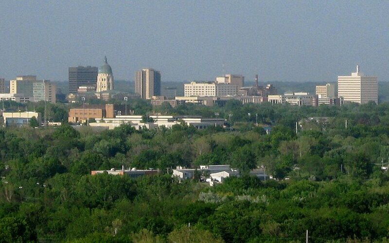 Kansas State Capitol building in Topeka with its copper dome surrounded by government office buildings and mature trees