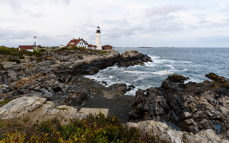 Portland Head Light lighthouse on rocky coastline with crashing waves in Cape Elizabeth Maine