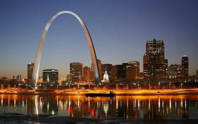 Gateway Arch towering over the St. Louis riverfront at sunset