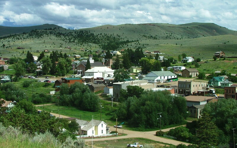 Panoramic view of the historic gold mining town of Virginia City Montana nestled in a valley with green mountains in the background