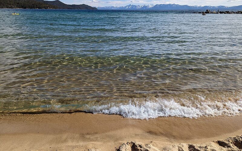 Crystal clear waters of Lake Tahoe with Sierra Nevada mountains in the background