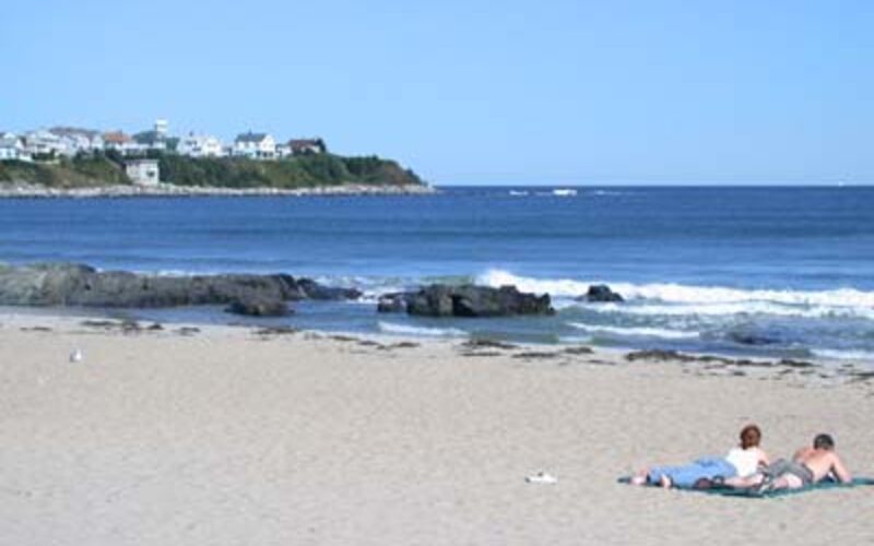 Sandy beach with sunbathers and rocky outcrops on the New Hampshire coast
