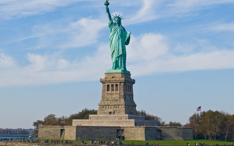 Statue of Liberty on Liberty Island with American flag and visitors