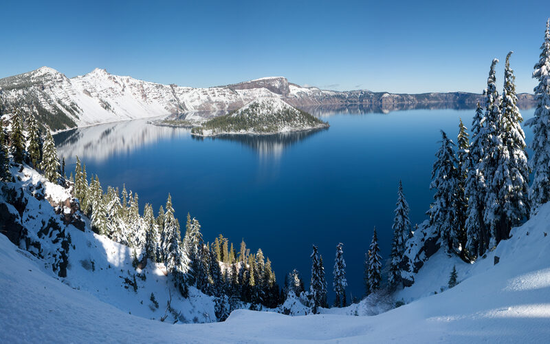 Crater Lake National Park in Oregon with deep blue water filling the volcanic caldera and Wizard Island