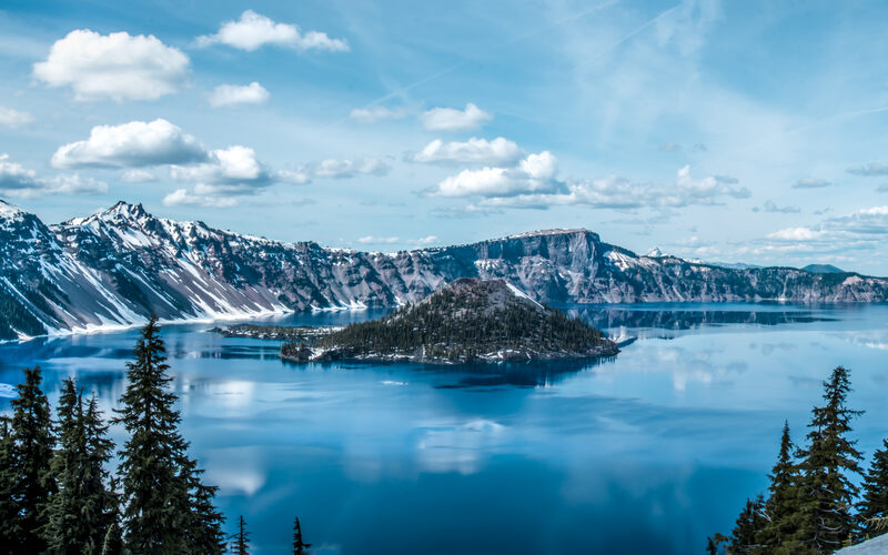 Crater Lake and Wizard Island in southern Oregon with snow-capped crater rim and deep blue water