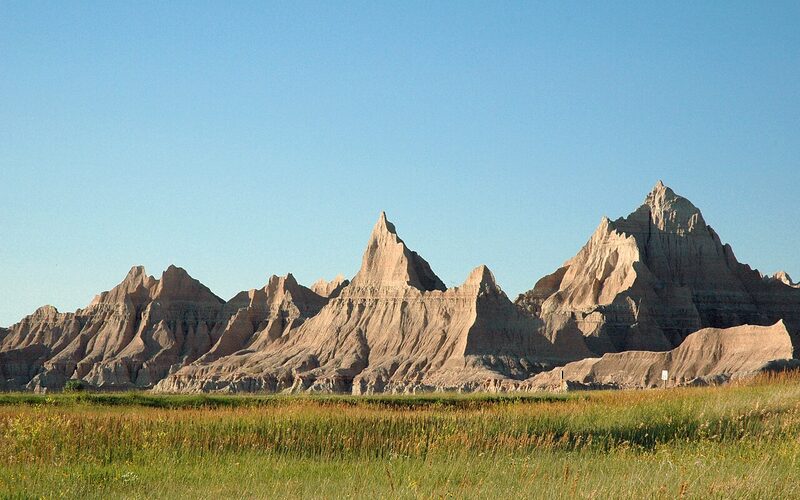 Badlands National Park formations at golden hour with prairie grassland in South Dakota