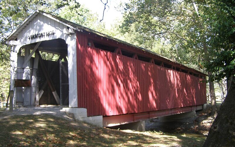 Historic covered bridge in rural Vermont surrounded by fall foliage