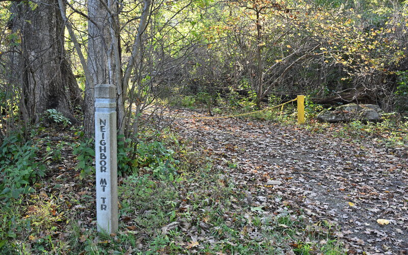 Neighbor Mountain Trail marker on a leaf-covered hiking trail in Shenandoah National Park