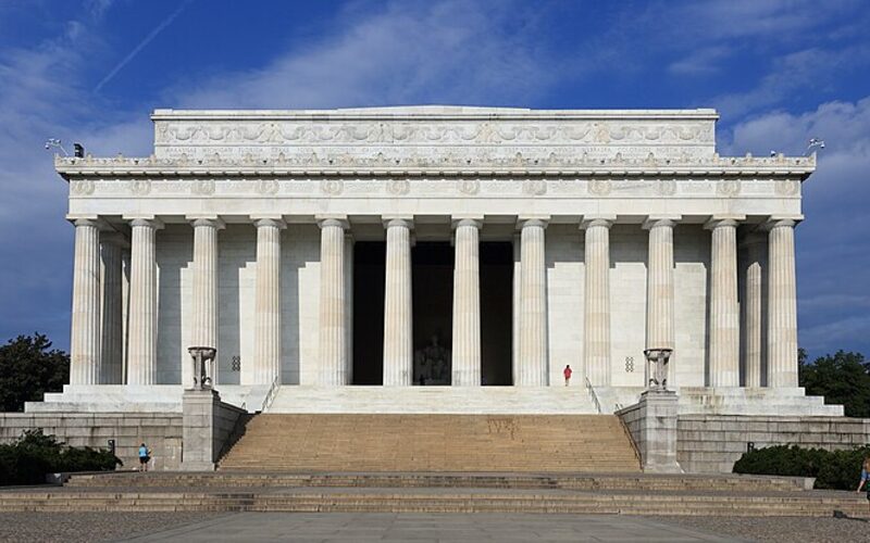 The Lincoln Memorial in Washington DC at dusk, with the reflecting pool stretching toward the Washington Monument